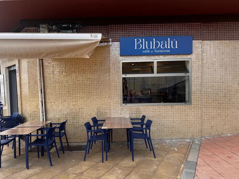 Fachada de Blubalú con el cartel azul y la terraza de sillas azules