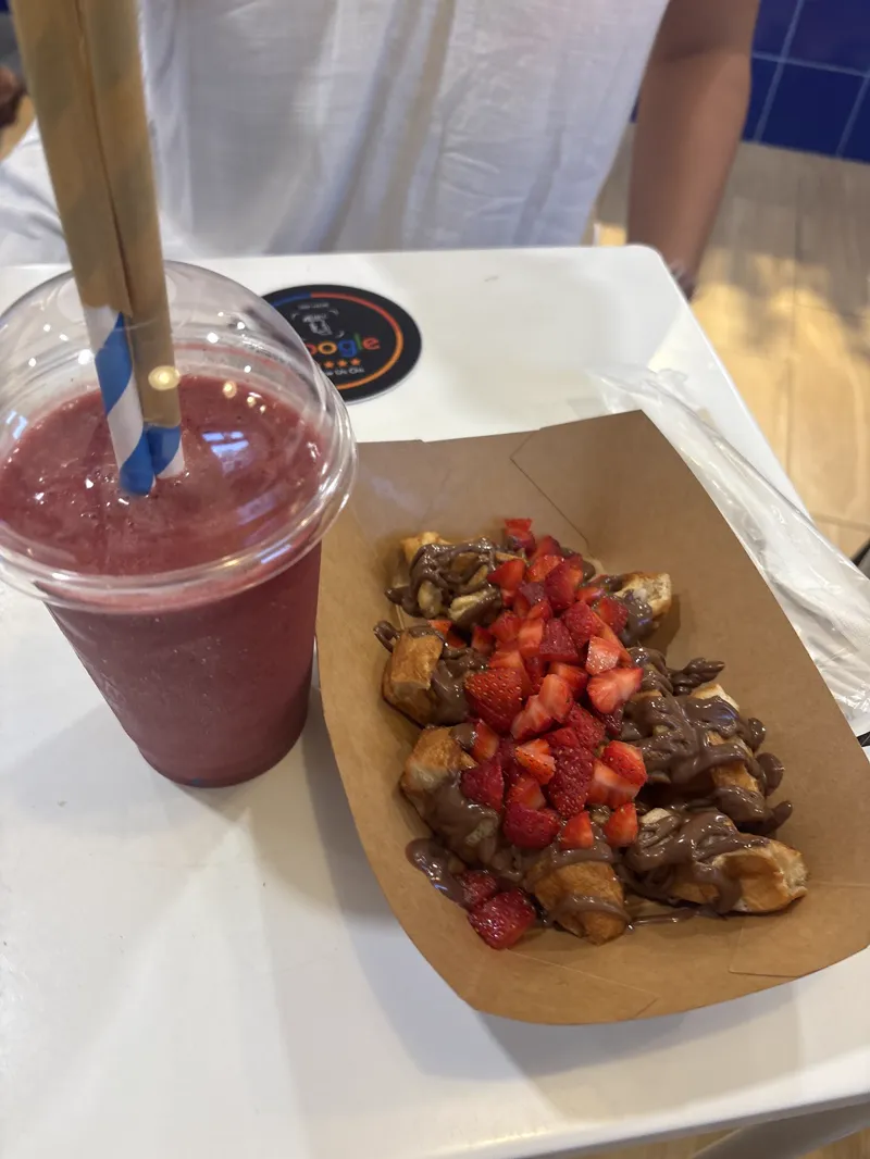 Smoothie de frutos rojos junto a un gofre con fresas y chocolate